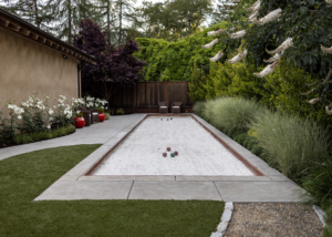 Elegant small bocce court with unique hardscape and lawn geometry and border planting