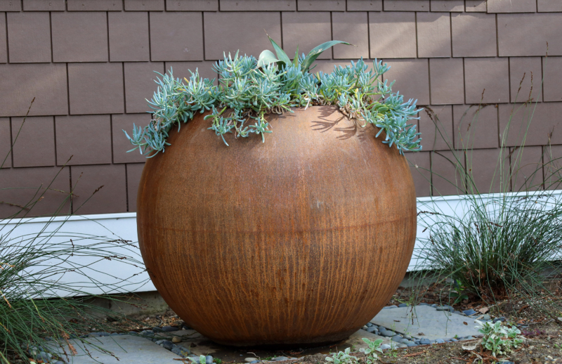 Modern rust-colored planter with succulents by Montgomery Robbins – sculptural garden element in custom landscape design