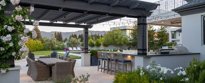 outdoor dining area with rose trees climbing the wooden pergola next to the cook center