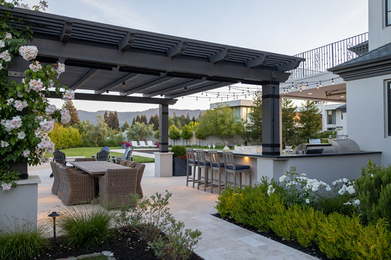 Luxury outdoor kitchen and pergola with dining area and garden landscaping by Montgomery Robbins