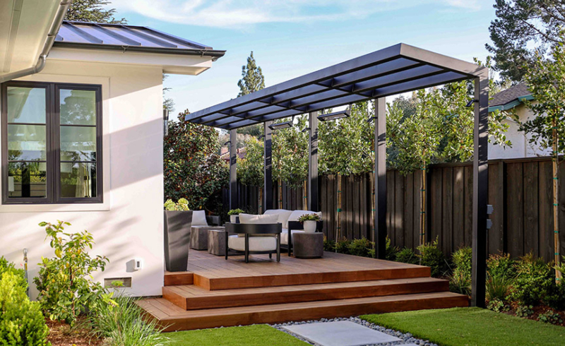Modern backyard deck with sleek metal pergola and outdoor seating by Montgomery Robbins.