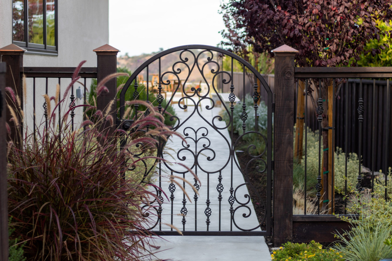Decorative wrought iron garden gate with custom landscape path by Montgomery Robbins