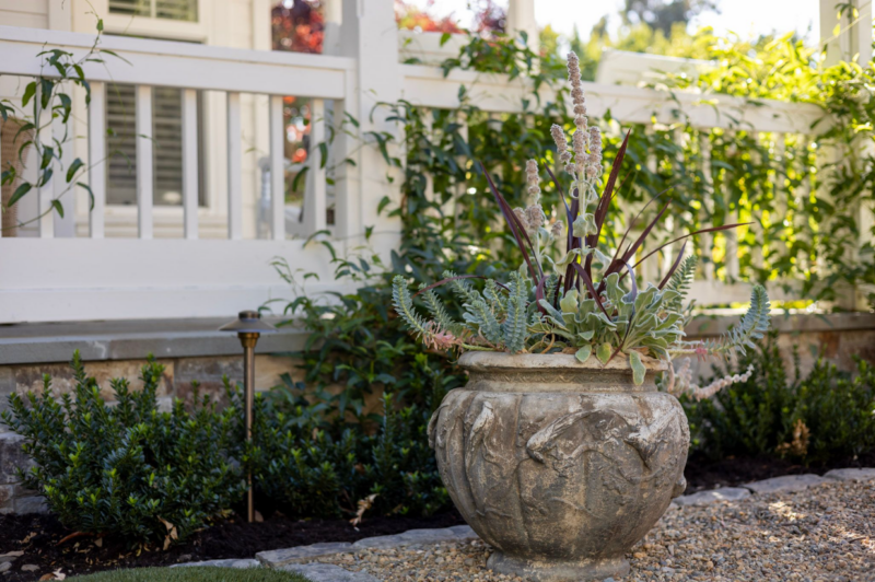 Rustic stone planter with succulents in a gravel courtyard by Montgomery Robbins – elegant garden detail in custom landscape design