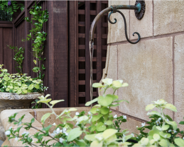 Ornamental water spigot flows into a fountain basin