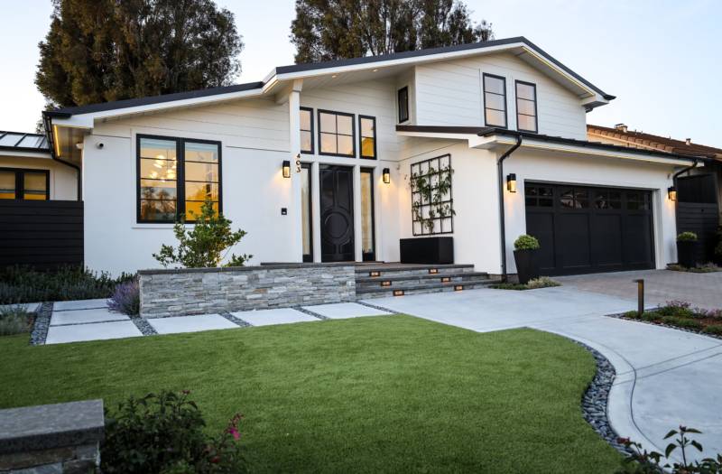 Modern front yard landscaping and exterior design by Montgomery Robbins featuring stone accents and artificial turf.