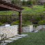 Custom wood pergola and stone accented retaining and bar lend elegance and structure