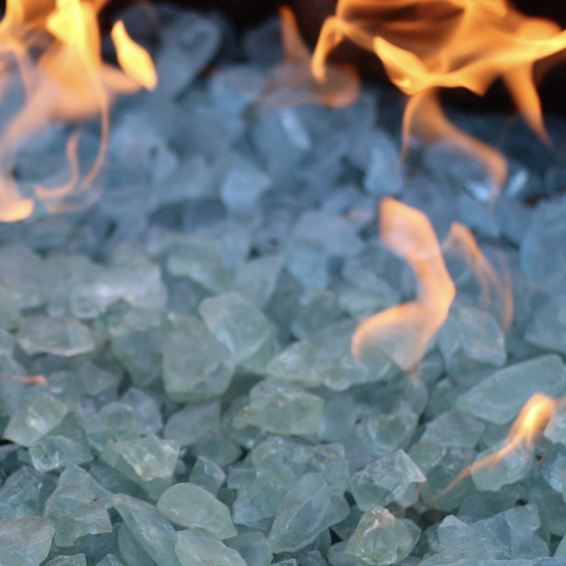 Close-up of fire glass crystals with flames, featured in a modern fire pit by Montgomery Robbins.