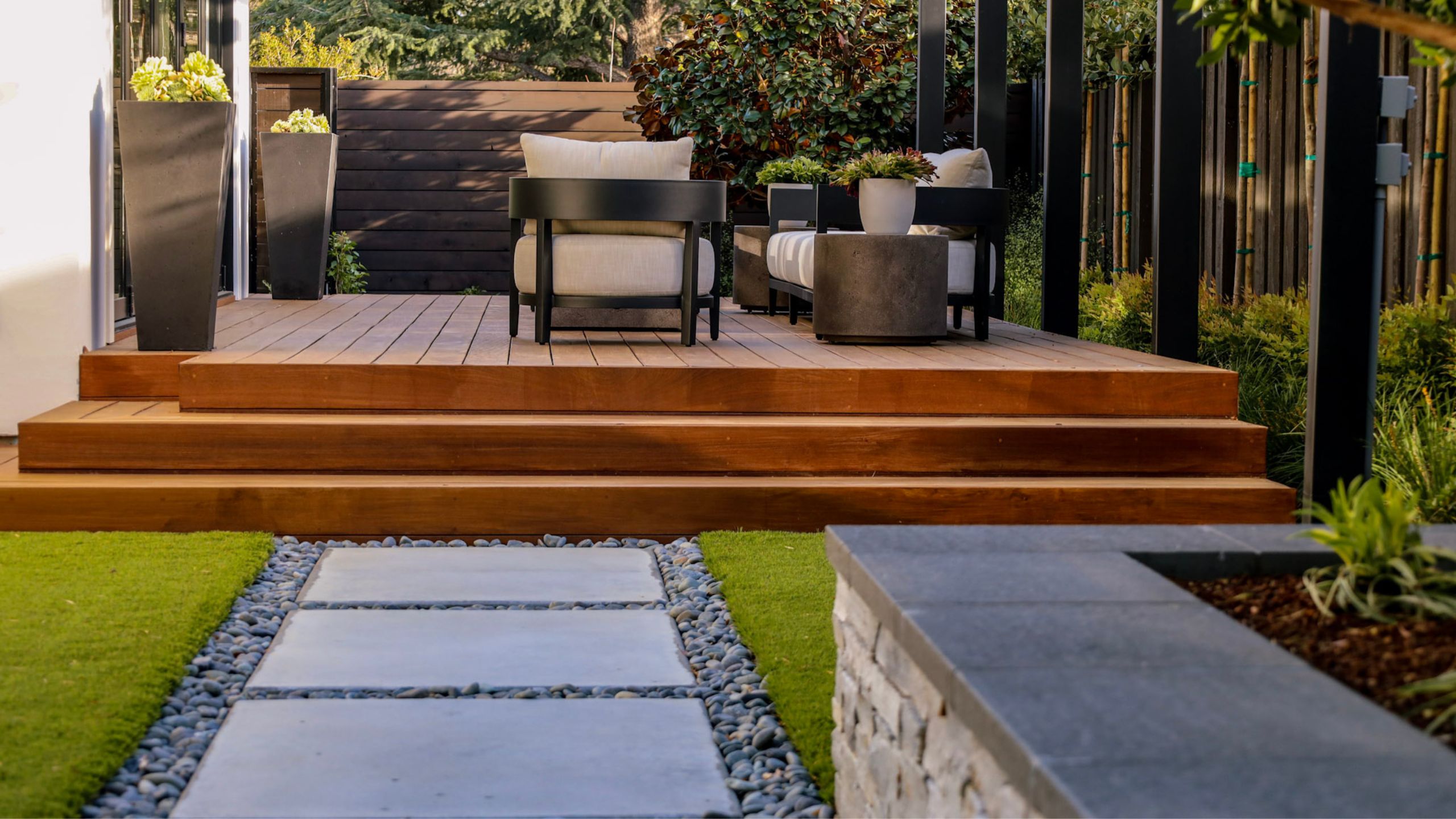 Contemporary outdoor living space with wood deck and modern concrete pavers