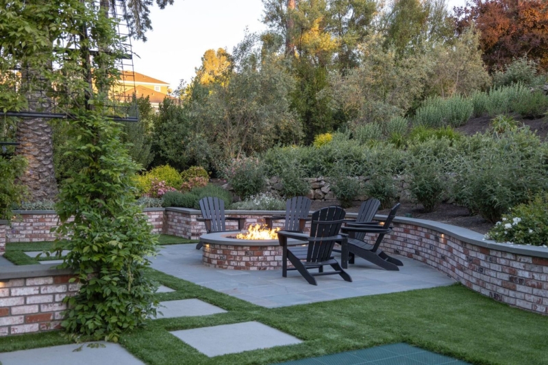 Fire Features in Bay Area Landscape Architecture by Montgomery Robbins, Inc. featuring a curved brick fire pit terrace with integrated seating, stone paving, and layered planting design in a Bay Area hillside garden.