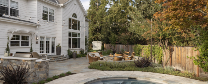 Elegant backyard design by Montgomery Robbins featuring custom pool, spa, outdoor kitchen, and cozy fire pit seating under string lights