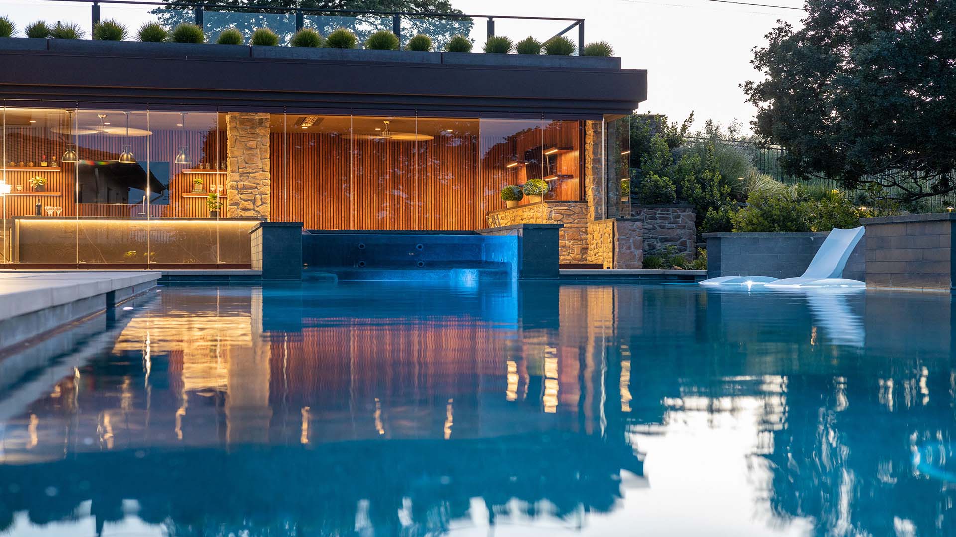 Montgomery Robbins, Inc. residential landscape architecture in the Bay Area, California featuring a custom backyard design with geometric concrete step pads set in lush lawn, structured foundation plantings, outdoor dining patio, and a covered pergola lounge — refined outdoor living design for high-end homes in Alamo, Danville, Lafayette, Walnut Creek, Marin, and the Peninsula.