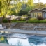Modern backyard pool and garden design by Montgomery Robbins, Inc., a leading residential landscape architecture firm in Alamo, California. This luxury outdoor living space features a sleek swimming pool with integrated spa, custom stone hardscape, terraced retaining walls, and layered plantings that frame the home. Comfortable lounge seating, lush greenery, and seamless transitions from poolside to elevated garden areas showcase Montgomery Robbins’ expertise in creating high-end residential landscapes that balance beauty, function, and California lifestyle design.