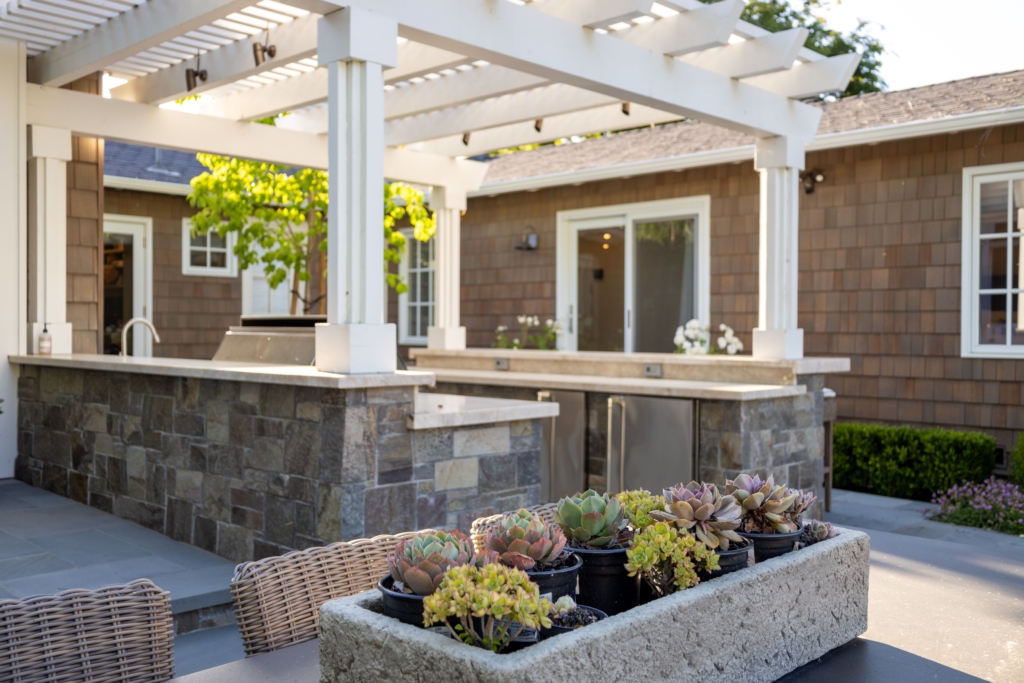 Cookbooks and garden vegetables on outdoor countertop by Montgomery Robbins