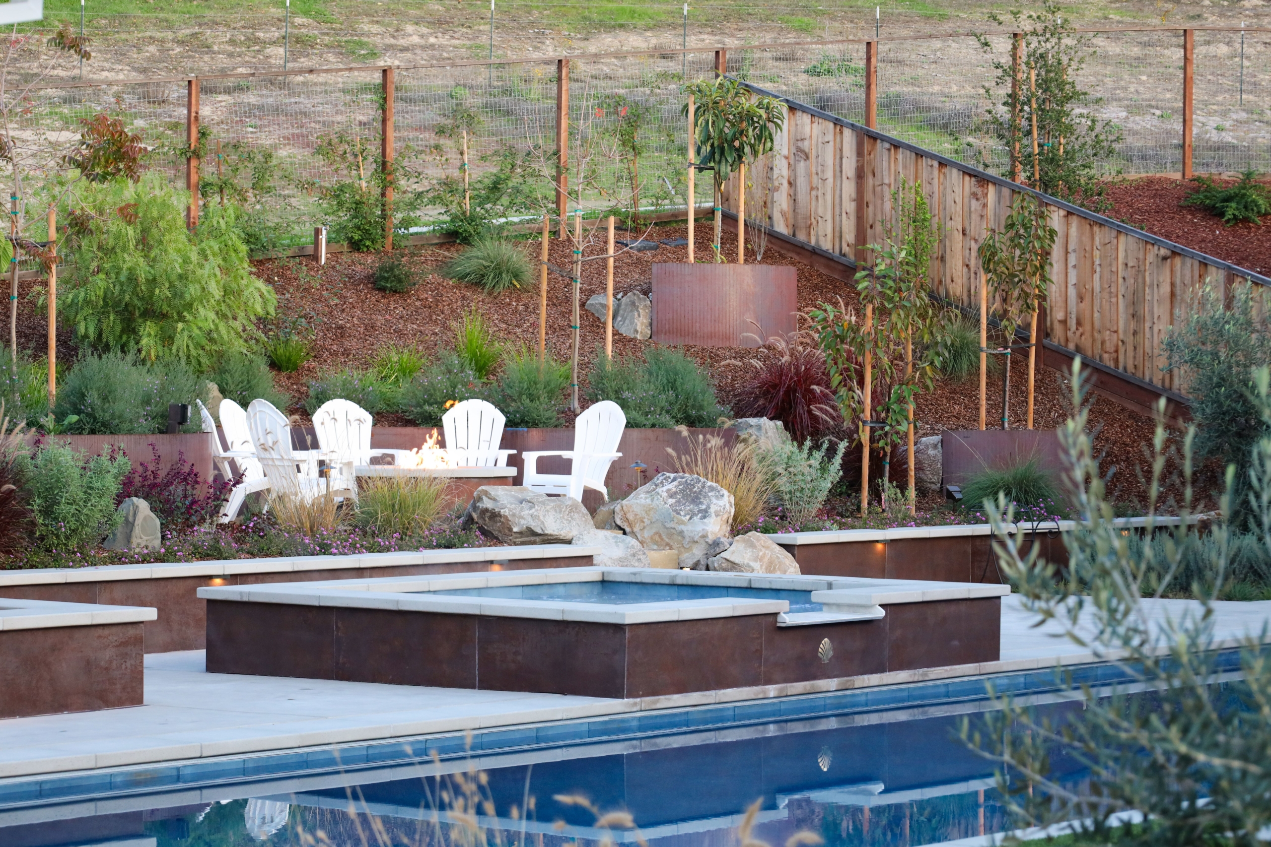 Luxury Bay Area residential landscape architecture featuring custom Corten steel planters and terraced retaining walls, integrated seating, and layered, contemporary planting design.