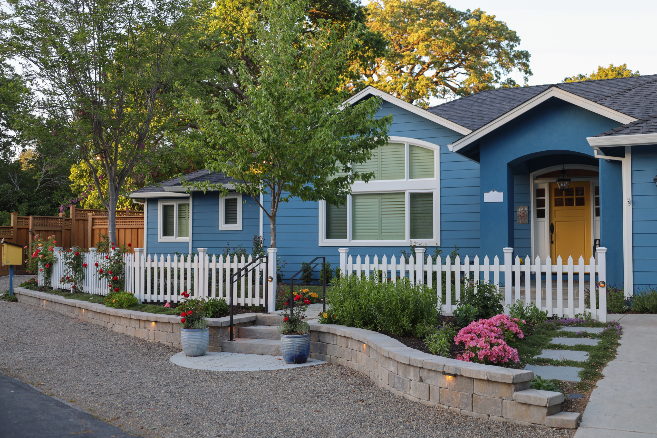 Brick and stone entry garden by Montgomery Robbins featuring classic lantern lighting, drought-tolerant plants, and a warm, welcoming landscape design.