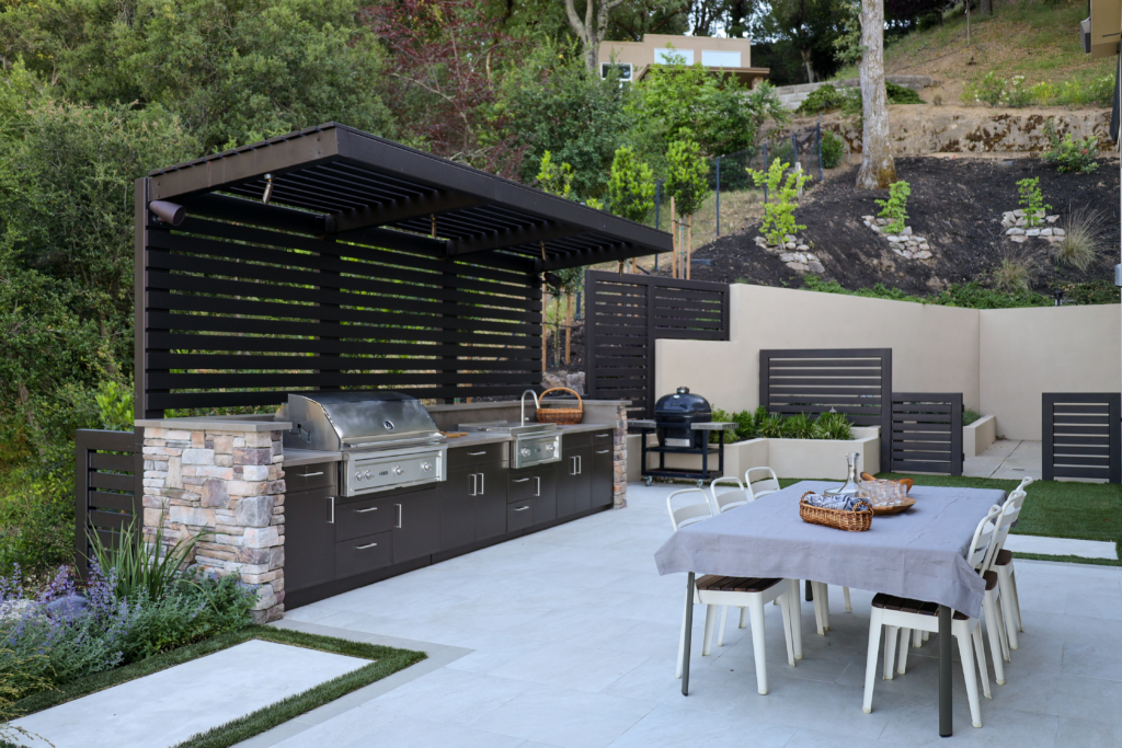 Outdoor kitchen with stainless steel grills, dark stone countertop, and appetizer setup by Montgomery Robbins
